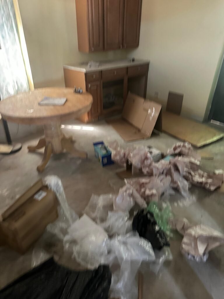 Kitchen and dining area with packing materials and clutter on the floor before cleanout