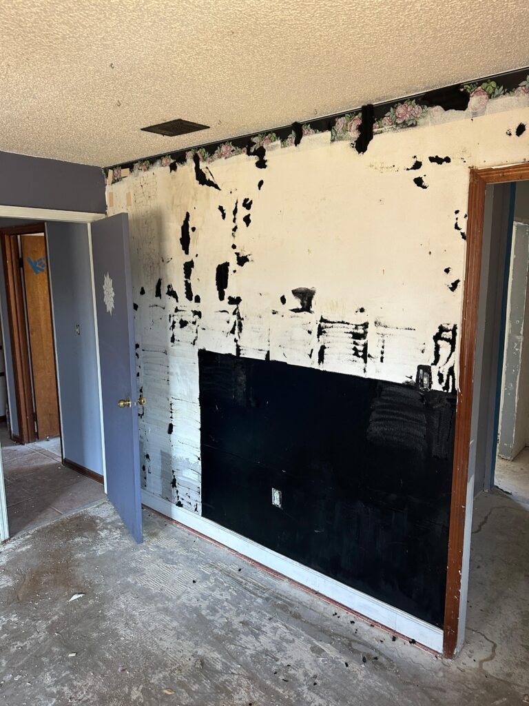 Damaged wall with peeling wallpaper before Palm Bay junk removal and demolition repair