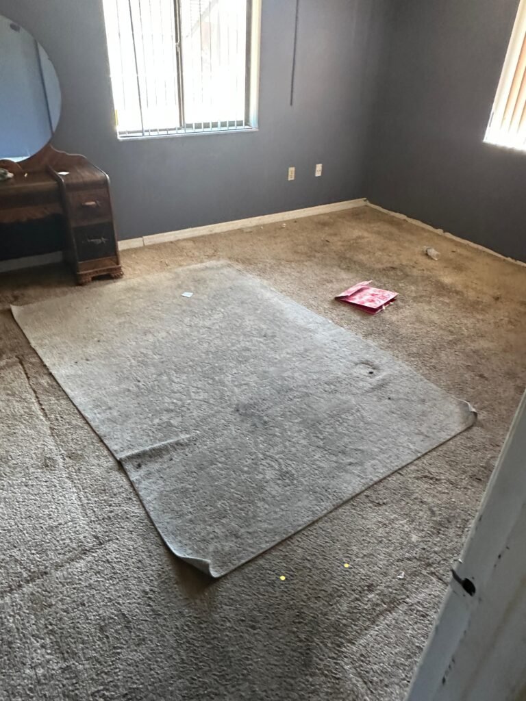 Empty bedroom with old carpet padding and dresser before cleanout