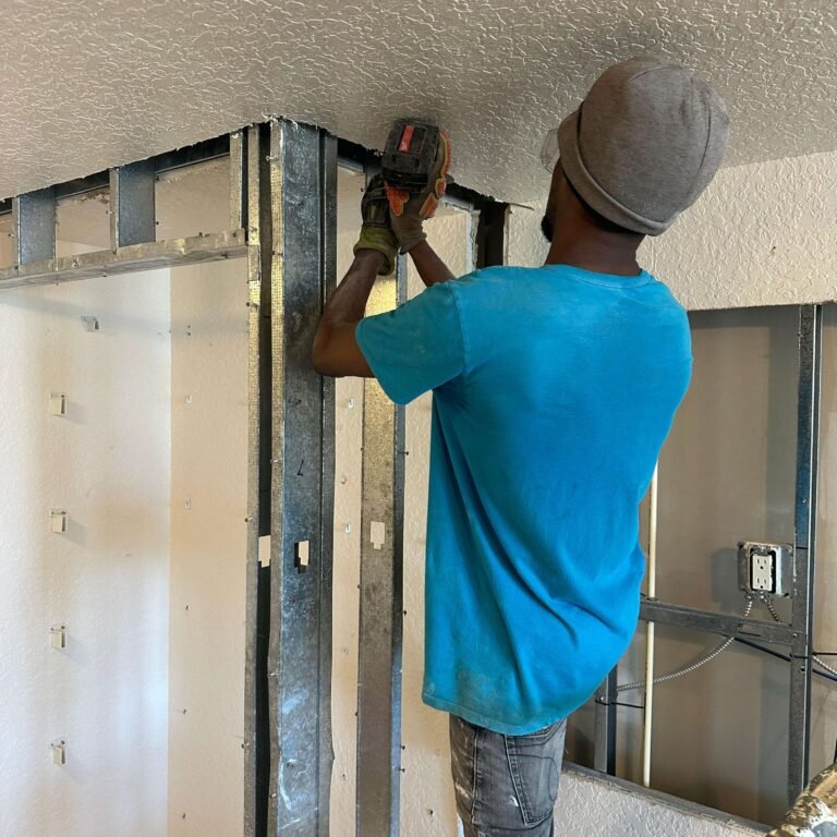 Worker removing interior framing during condo demolition